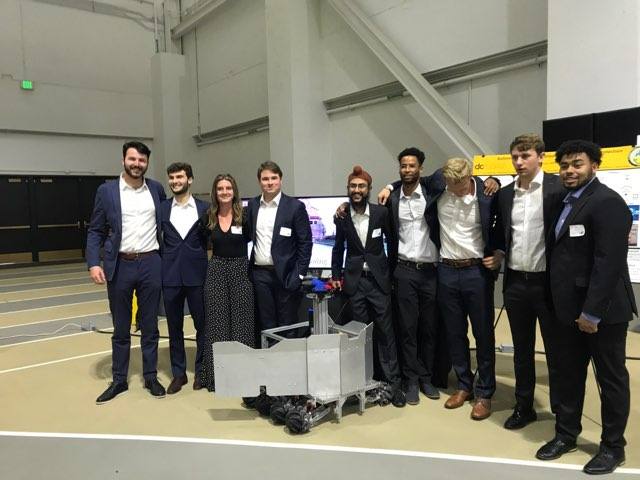 The Autonomous Defense Vehicle senior project team standing behind the completed vehicle at the final showcase